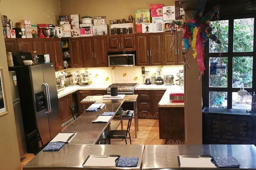 A kitchen with wooden cabinets, stainless steel appliances, and a window with curtains. 1