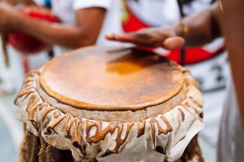 A close-up of a drum with carved patterns on its surface and a rope wrapped around its body. 1