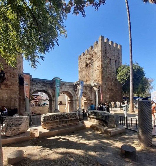 An ancient stone structure with arches and columns, surrounded by trees and a clear sky. 4