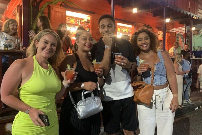 A group of people at an outdoor event, possibly a bar or restaurant, with drinks in hand. 4