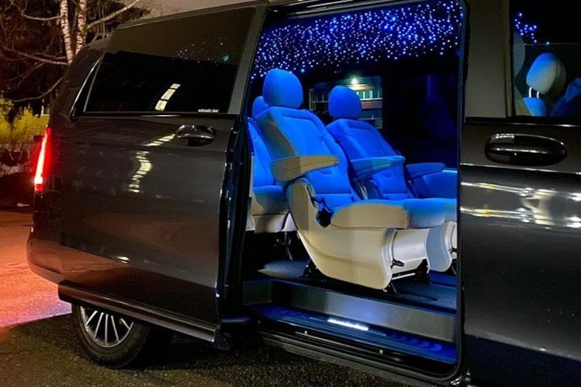 Een voertuig met een open achterdeur, waarachter een blauw verlicht interieur met twee zitplaatsen zichtbaar is. 2