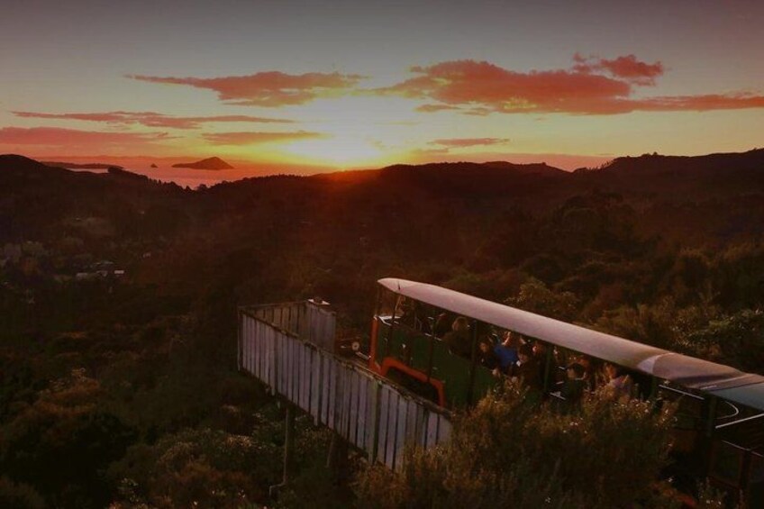 A train with passengers at sunset, surrounded by hills and vegetation. 3