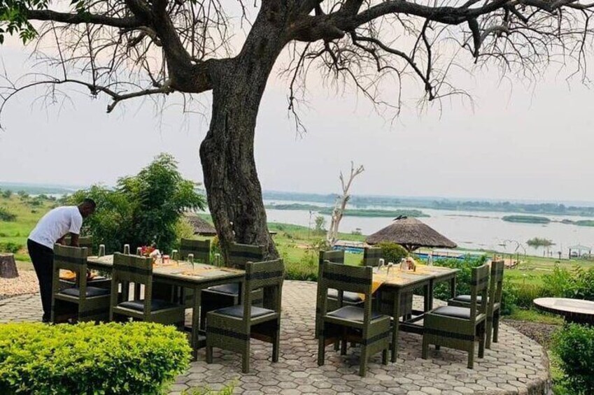 Chaises et tables pour les repas en plein air, placées sous un arbre, avec vue sur une rivière. 5