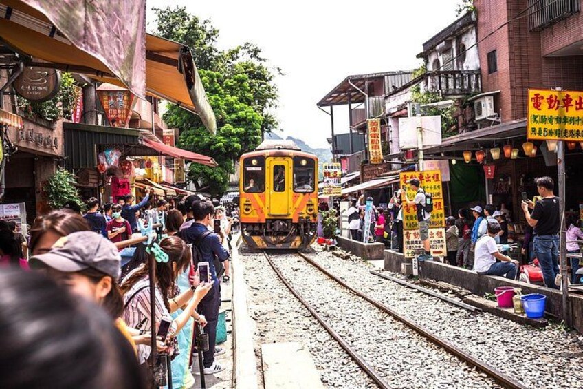 A train passing through a busy street with shops and people. 2