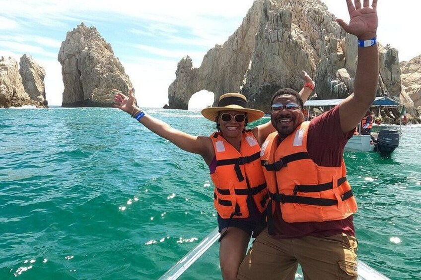 Dos personas en un bote con chalecos salvavidas, con acantilados rocosos al fondo. 2