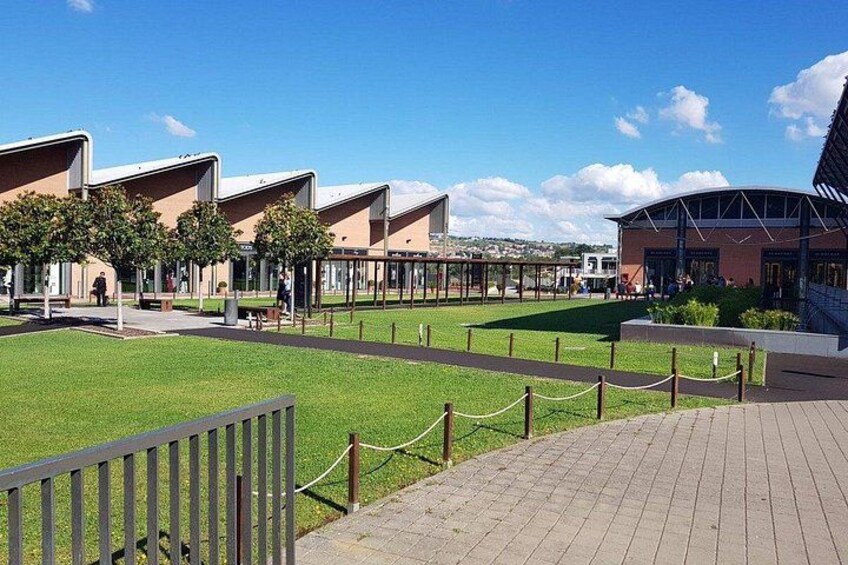 En modern byggnadskomplex med en central gräsyta, gångvägar och ett inhägnat område runt omkring. 3