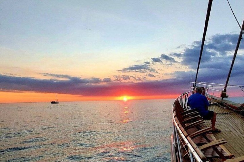 Tramonto sull'oceano con una barca a vela e una persona sul ponte. 4