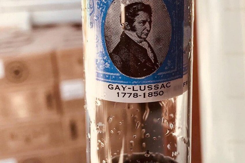 A bottle with a label featuring a portrait and text, including a name and dates. 1