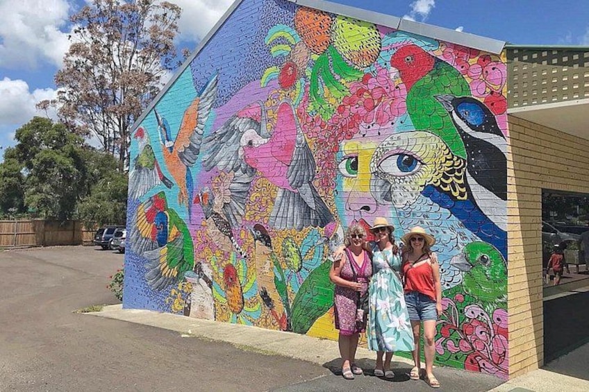 A colorful mural on a building's side, featuring birds and floral patterns. 4