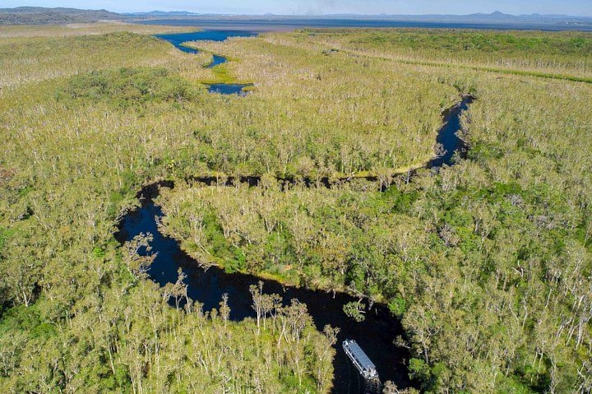 A river meandering through a marshy landscape with sparse vegetation. 1