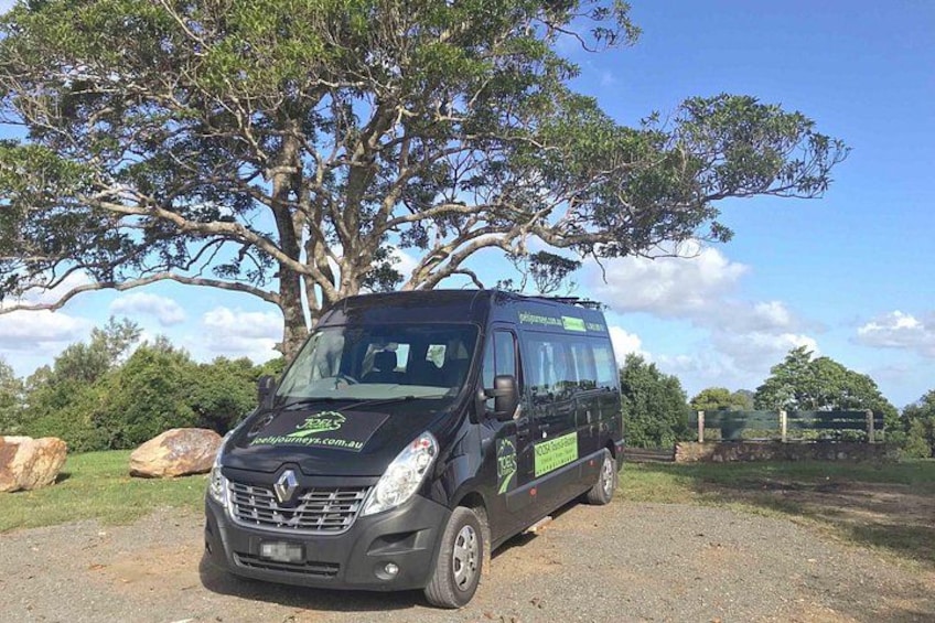 A black van parked on a gravel path with a large tree in the background. 2
