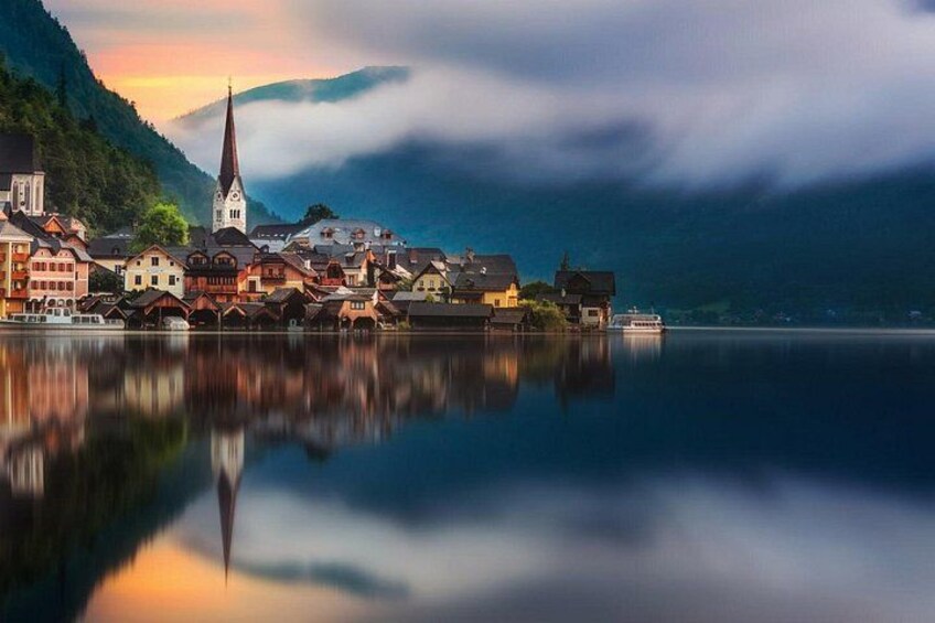 A serene lakeside town with a prominent church, calm water, and surrounding mountains. 2