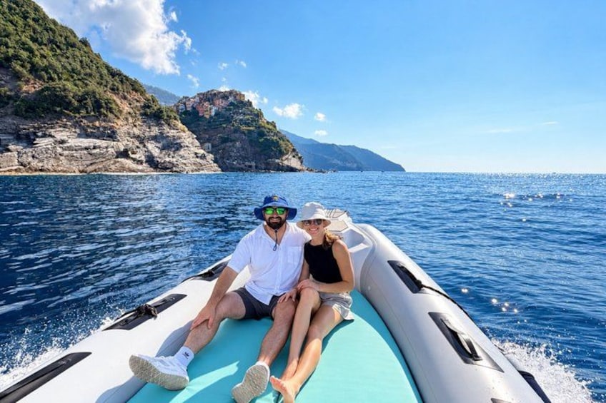 A couple on a boat with a rocky coastline and clear blue sky in the background. 3