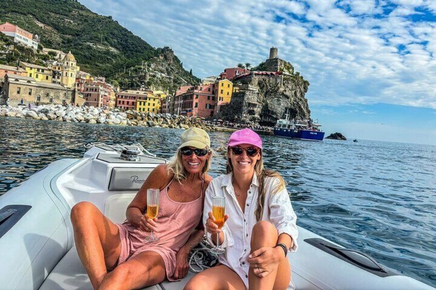Dos personas en un bote, con un pueblo costero y un castillo al fondo. 4