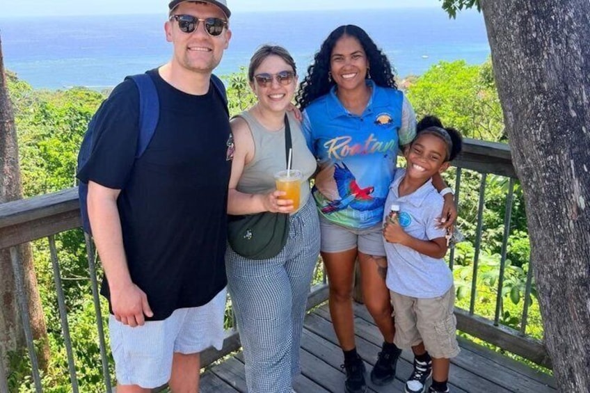 A family on a wooden deck with a view of the ocean. 1
