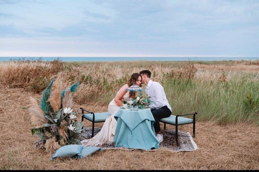 A couple dining at a table set outdoors with a view of the ocean. 1
