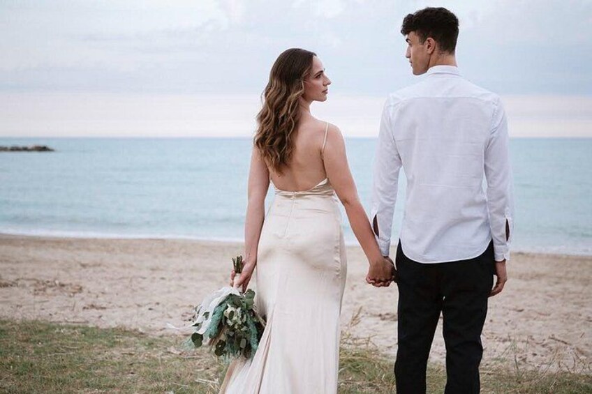 A couple holding hands on a beach with the ocean in the background. 2