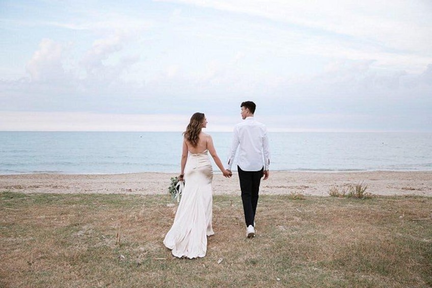 A couple walking on a beach with the ocean in the background. 5