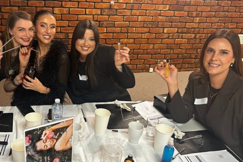 Three people sitting at a table with various items including cups, a bottle, and a picture frame. 2