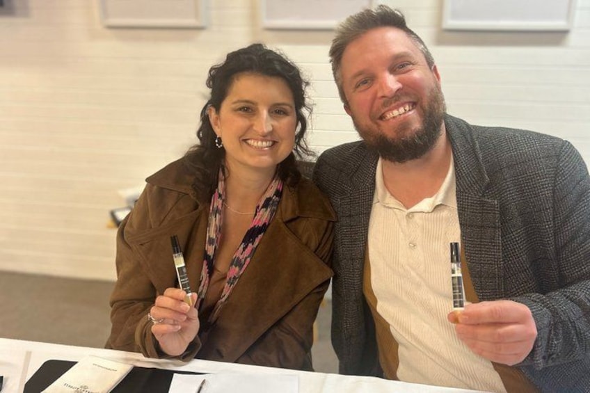 Two people sitting at a table with pens and papers. 5