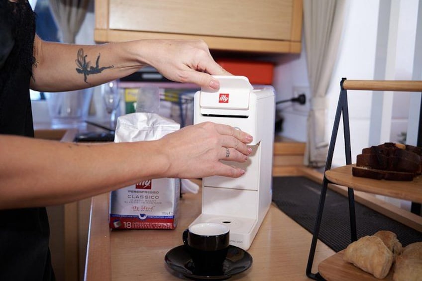 Una persona utilizza una macchina da caffè, con una confezione di cialde e una tazza sul bancone. 3