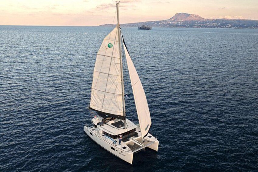 Un velero en un mar tranquilo con un paisaje montañoso al fondo. 3