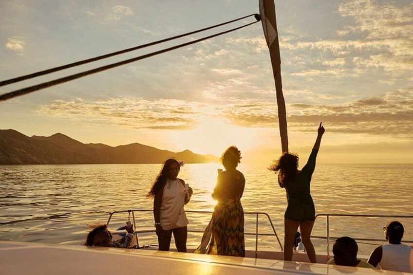 A sunset over a body of water with mountains in the background and people on a boat. 3