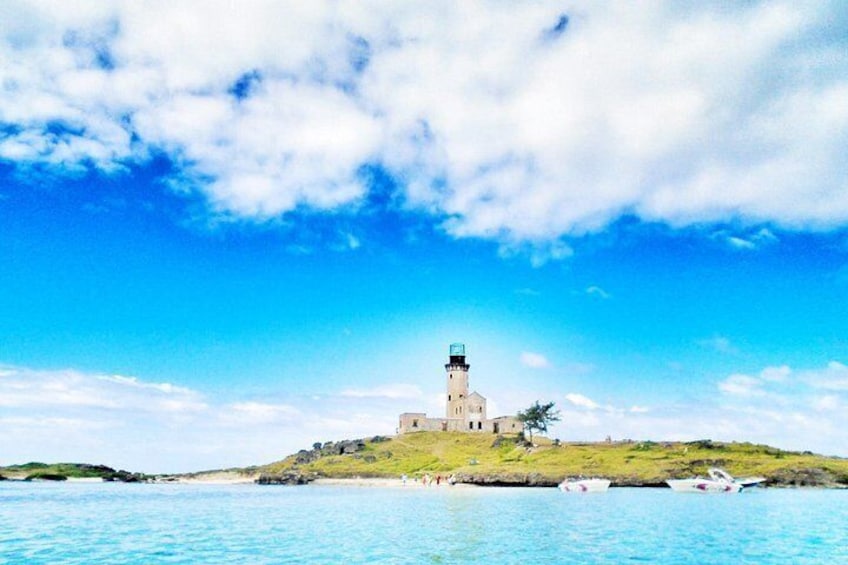A lighthouse on a grassy hill by the sea with a clear sky. 3