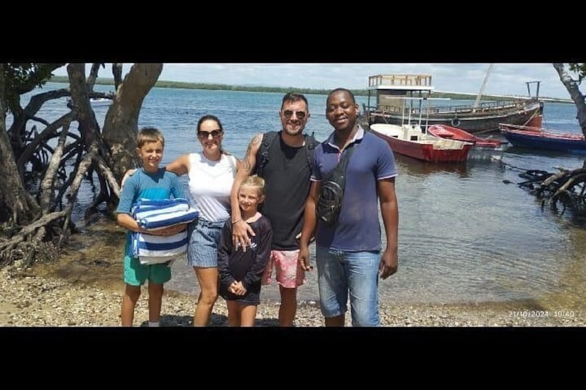 A family of five by a calm body of water with boats in the background. 5