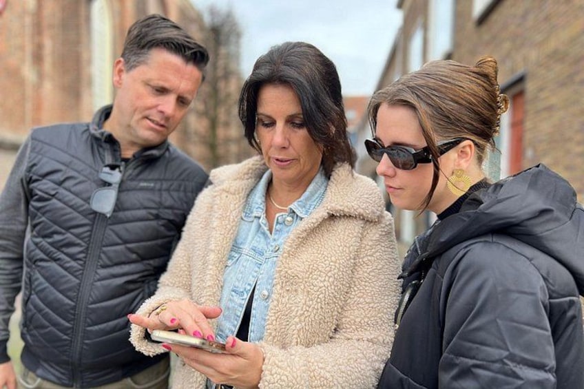 Three people standing outdoors, one holding a smartphone. 4