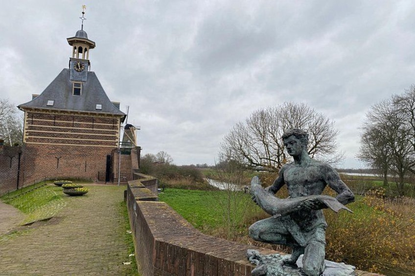 A brick building with a clock tower, a statue of a figure, and a pathway. 3