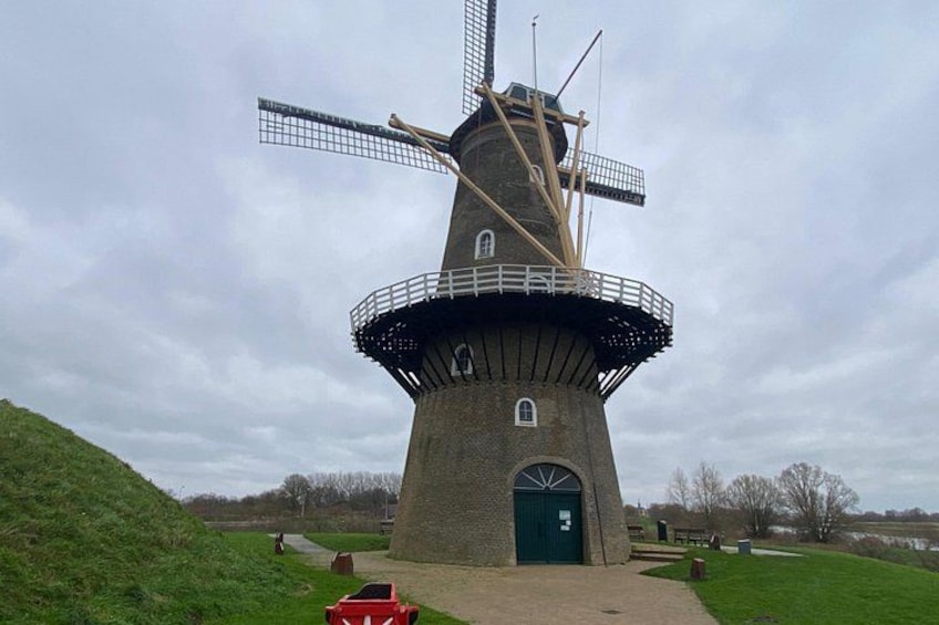 A traditional windmill with a large sail, a circular base, and a green door. 5