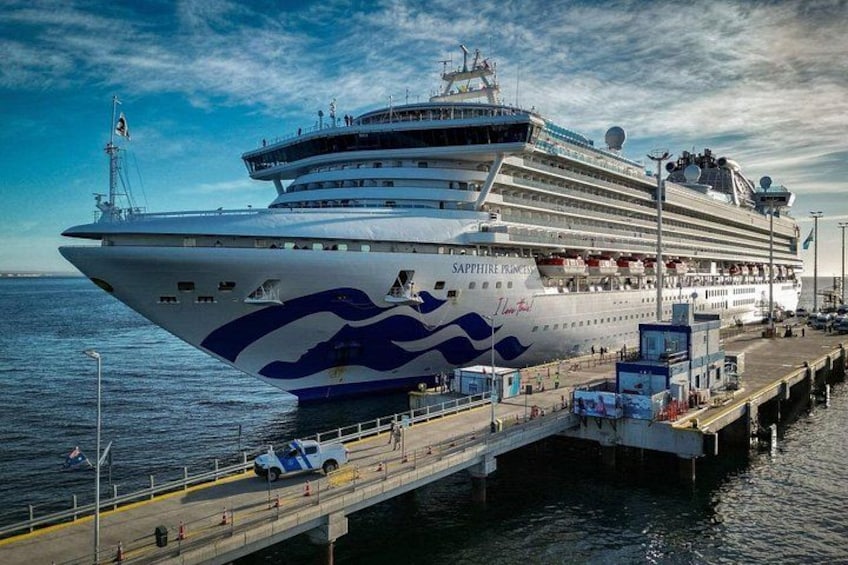 A large cruise ship docked at a pier with a clear sky. 1