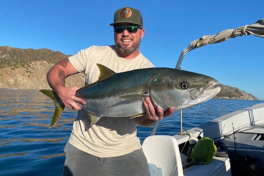 Une personne tenant un gros poisson sur un bateau, avec un paysage montagneux en arrière-plan. 3