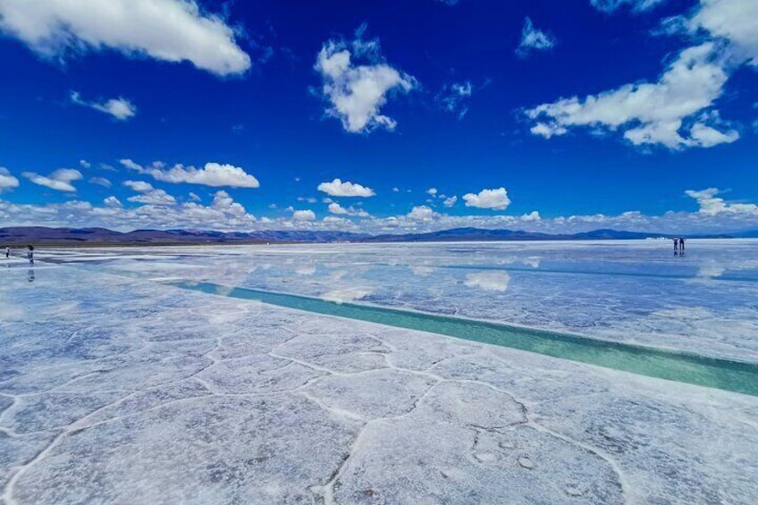 A salt flat with a clear blue sky and distant mountains. 3