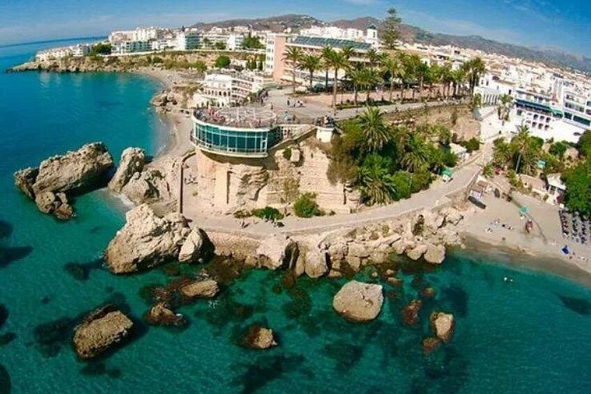 Un pueblo costero con un litoral rocoso, aguas azul cristalino y edificios a lo largo de la playa. 1