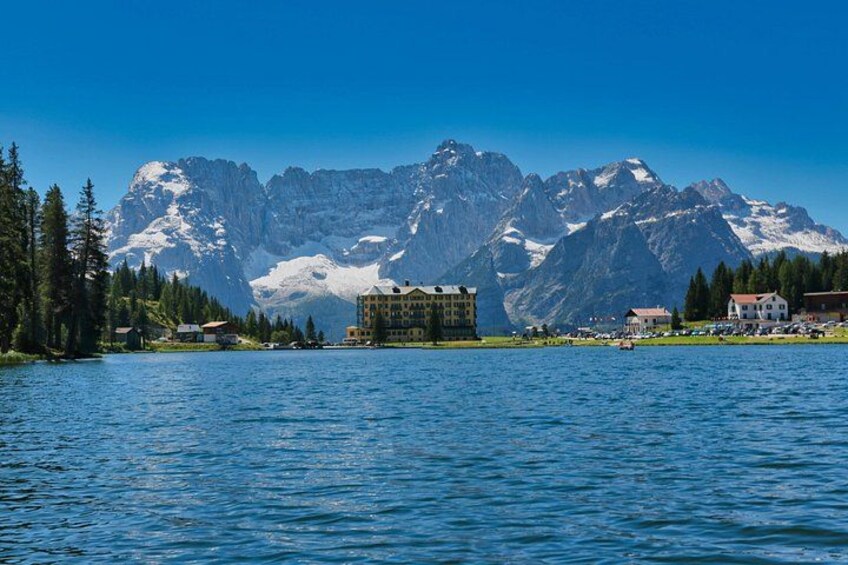 A lake with buildings and snow-capped mountains in the background. 2