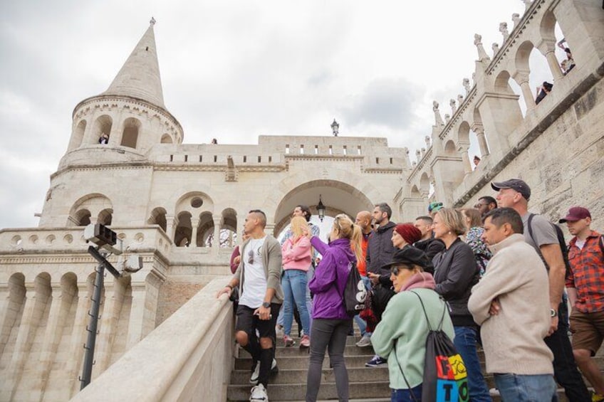 Un edificio histórico con arcos y una torre, personas subiendo por las escaleras. 1