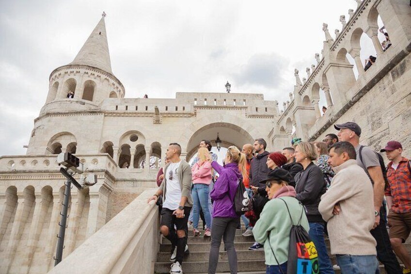 Un edificio histórico con una torre y arcos, rodeado de gente. 1
