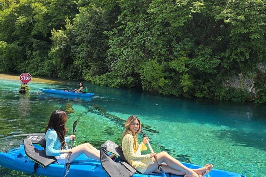 Two people in blue kayaks on a river surrounded by dense green foliage. 3