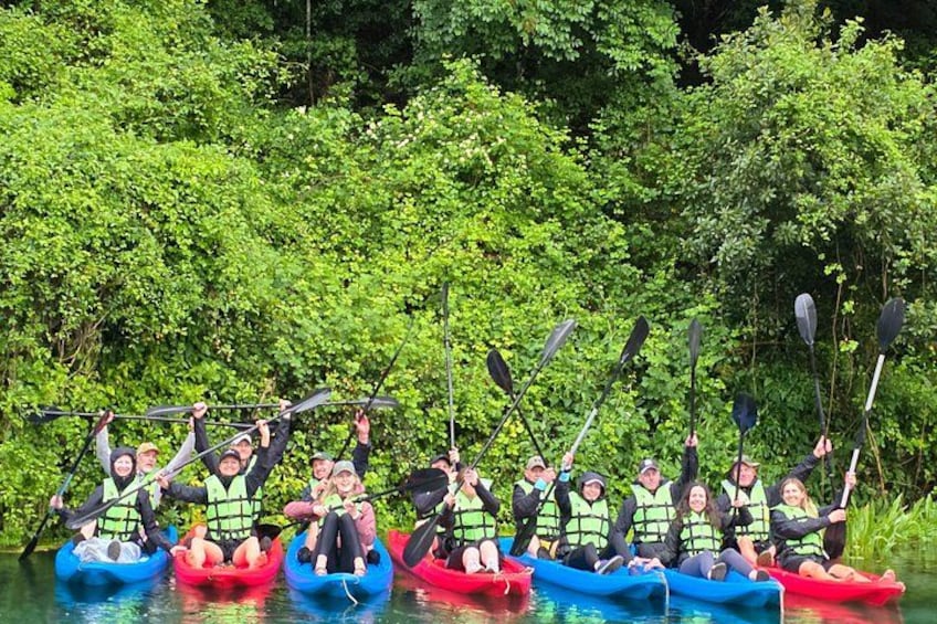 A group of people in kayaks on a river surrounded by dense greenery. 4