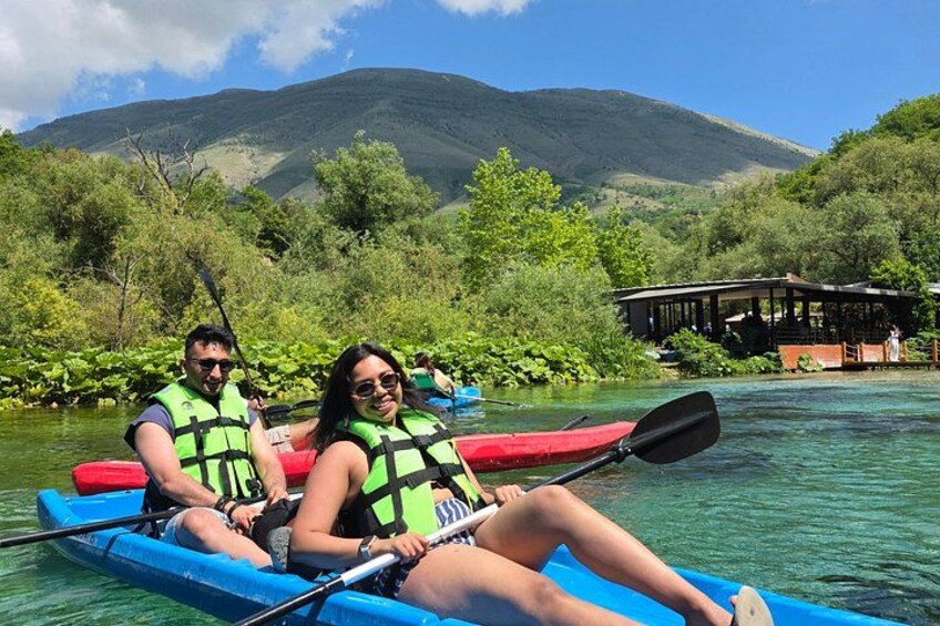 People kayaking on a river surrounded by greenery and hills. 2