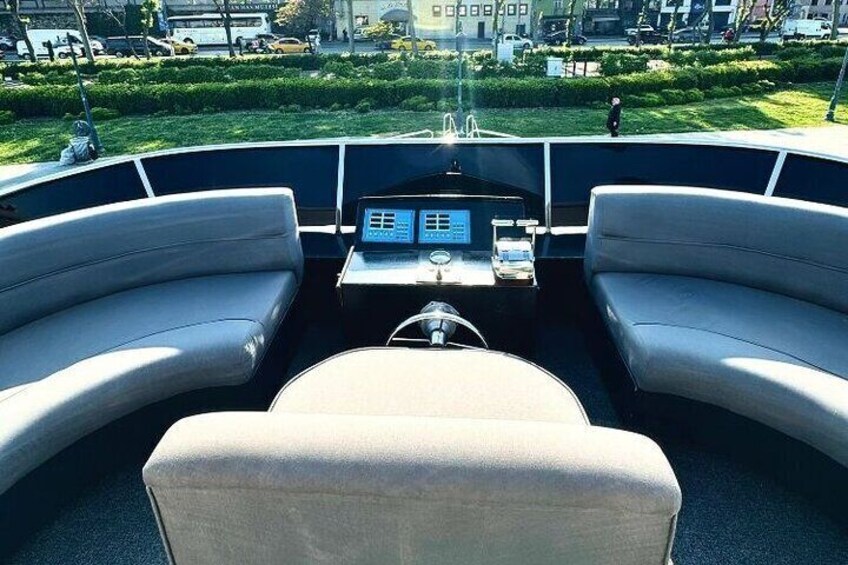 A boat's interior with two beige seats, a steering wheel, and a control panel. 5
