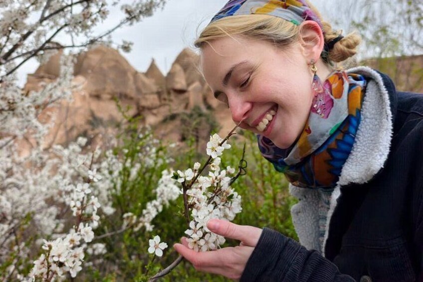 A person holding a branch of white flowers, with a mountainous landscape in the background. 2