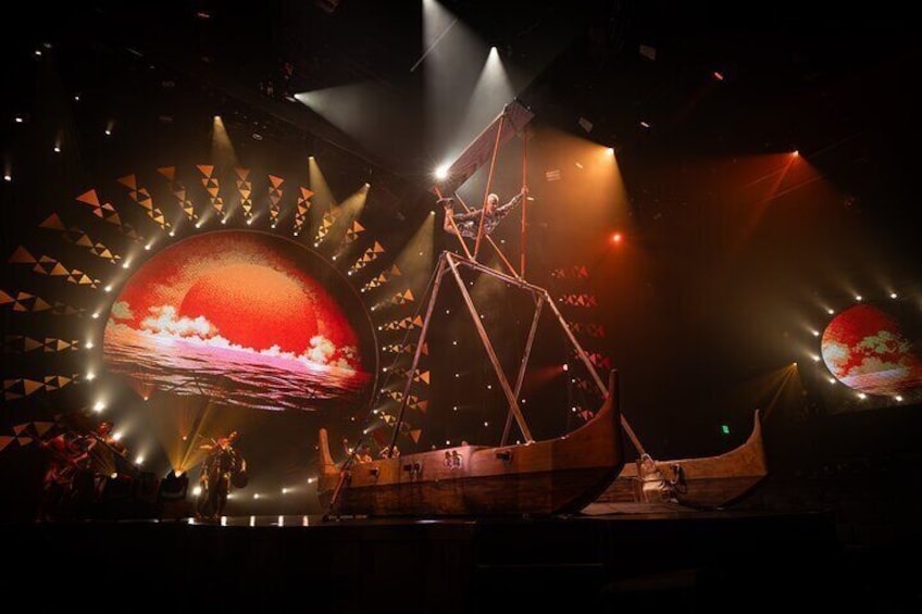 A ship on a stage with a large screen displaying a sunset. 4