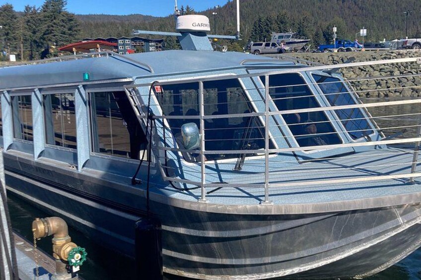 A boat docked at a marina with a clear sky and forested hills in the background. 2