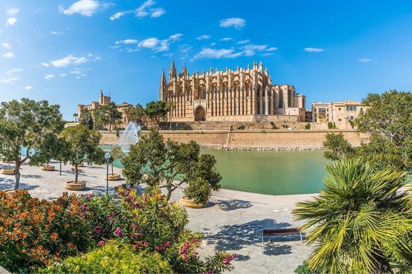 Una cattedrale storica dall'architettura gotica, circondata da un giardino curato con alberi e una fontana. 2