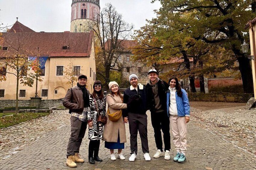 Un gruppo di persone su un sentiero lastricato, con un edificio storico e una torre sullo sfondo. 4