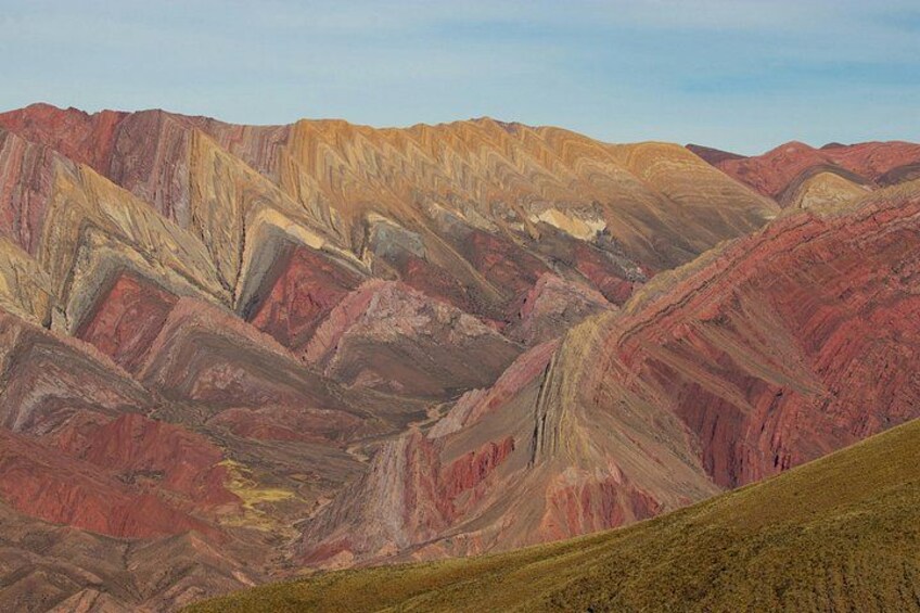 A mountainous landscape with layered rock formations in shades of red, yellow, and brown. 4