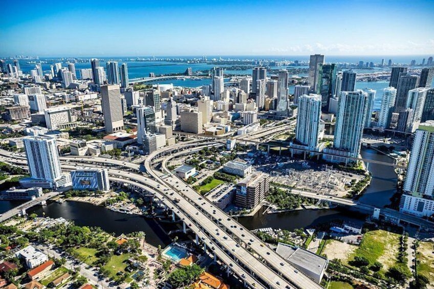 A cityscape with high-rise buildings, a river, and a highway interchange. 2